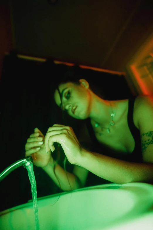 a woman drinking water from a faucet at night