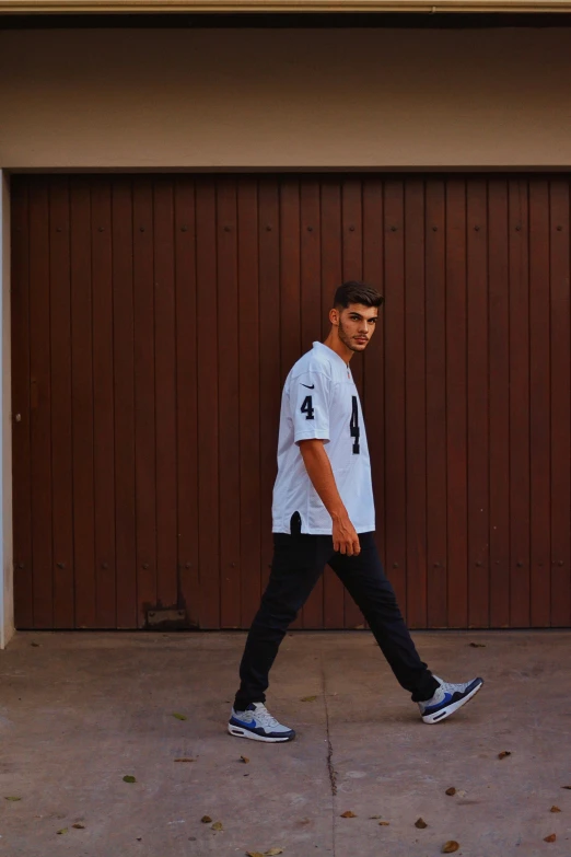 a man wearing a number four shirt walking with his shoes off