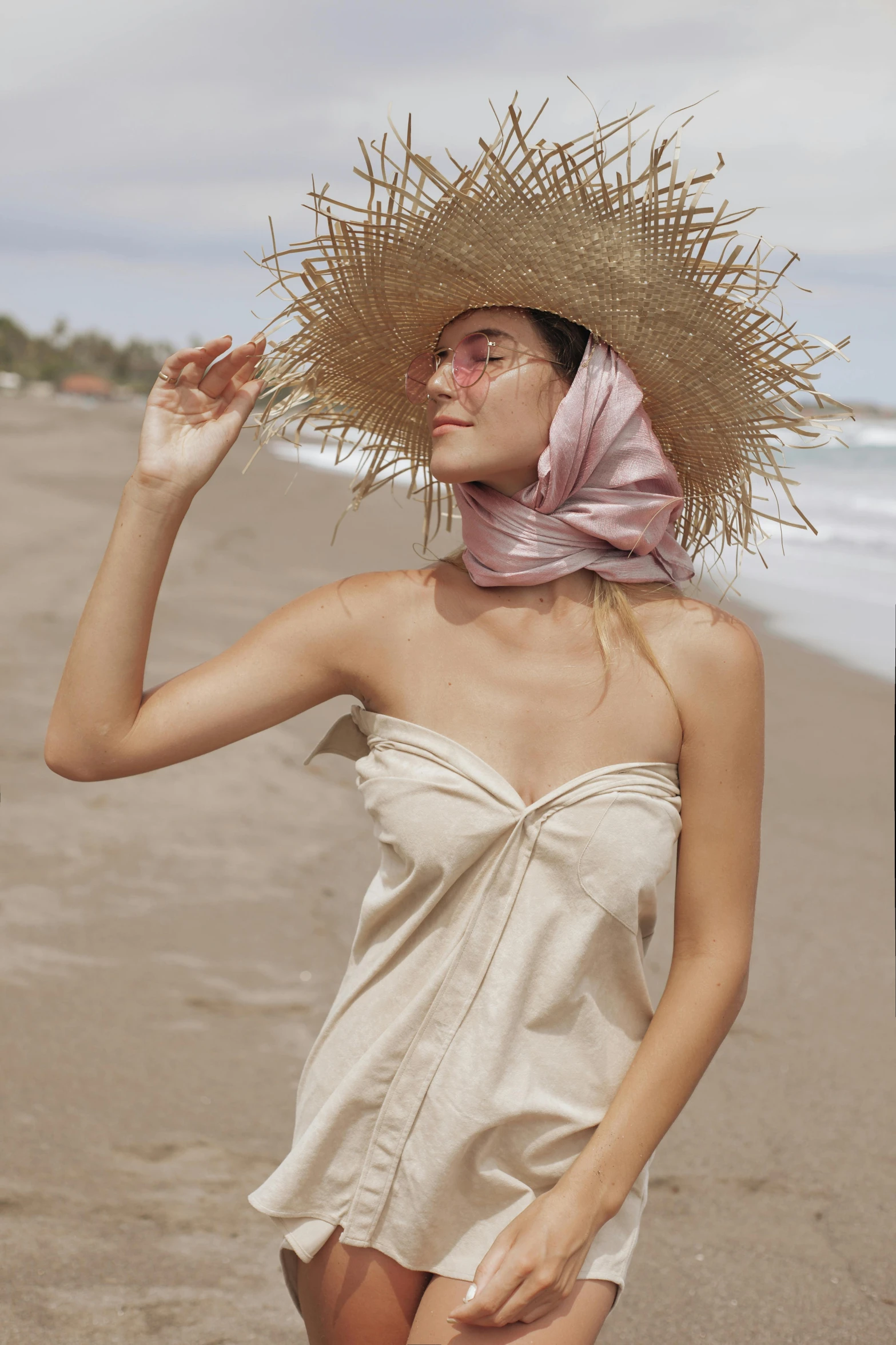 a woman at the beach in an under dress with straw hat