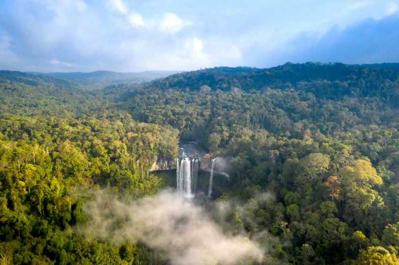 a waterfall with fog coming out in the sky