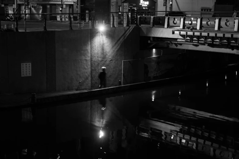 a black and white po of a person standing near a water way