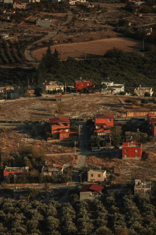 red houses on land surrounded by trees with an unpaved dirt road