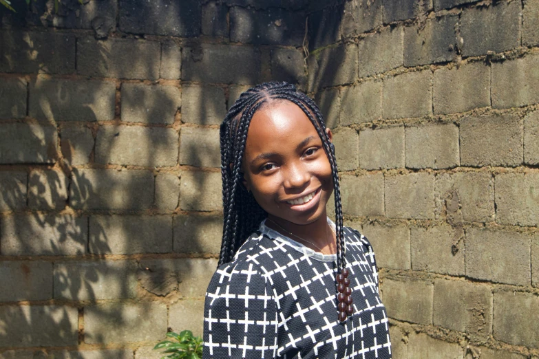 a smiling girl in front of a brick wall