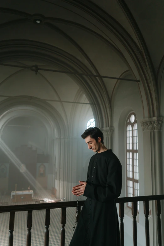 a man in black standing by railing on his cell phone