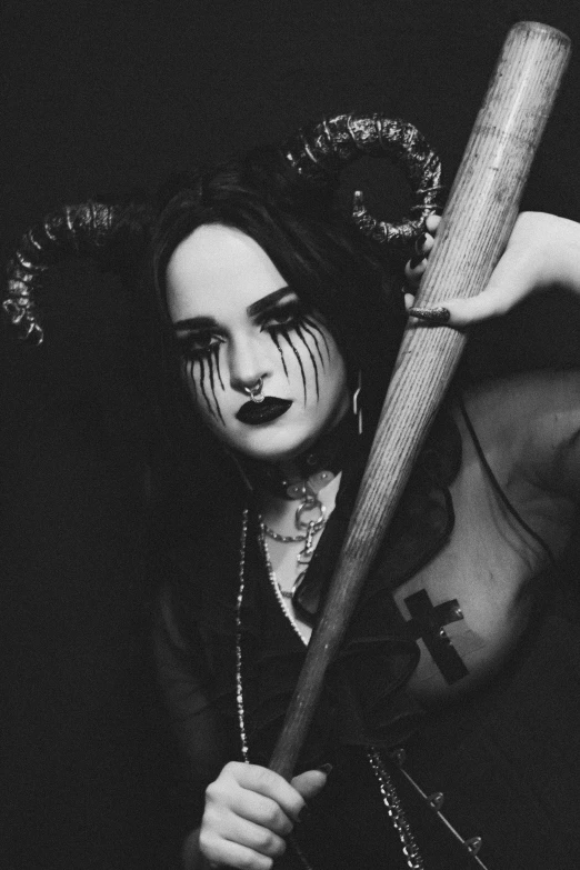 a woman with dark makeup and clown makeup holding a bat