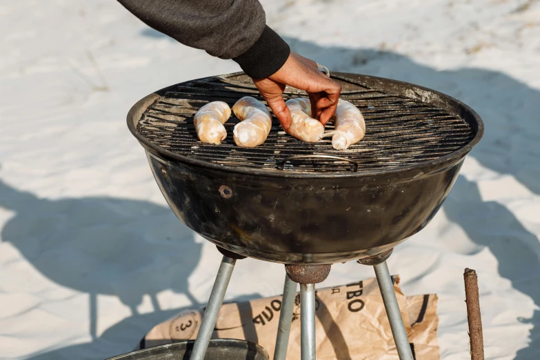 someone is preparing food on a charcoal grill