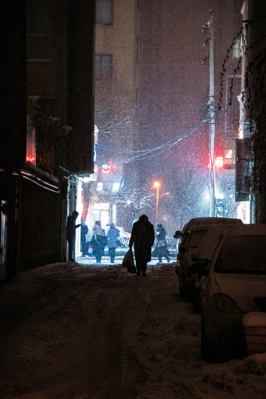 person with umbrella walking down a snow covered street at night