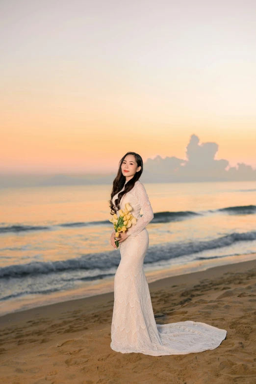 a woman stands on the beach at sunset with her bouquet