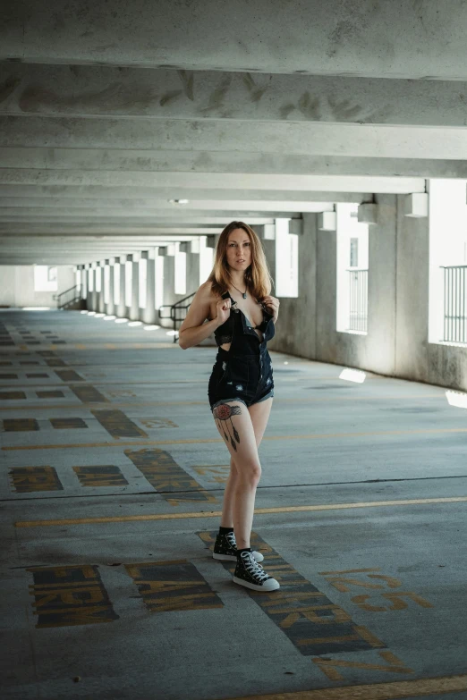 a woman in a skirt standing next to the side walk of a parking garage