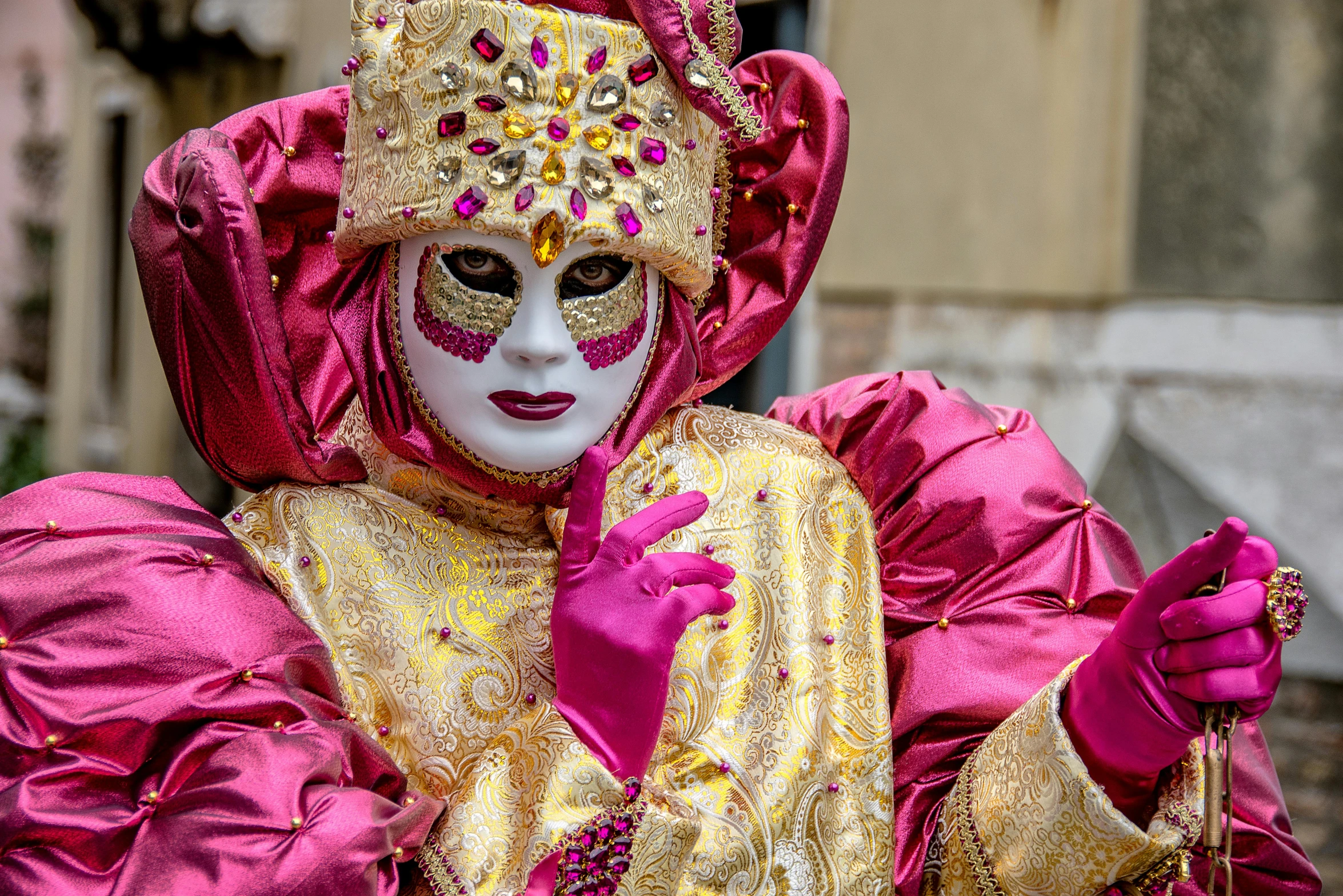 a person wearing a gold and pink face paint and mask