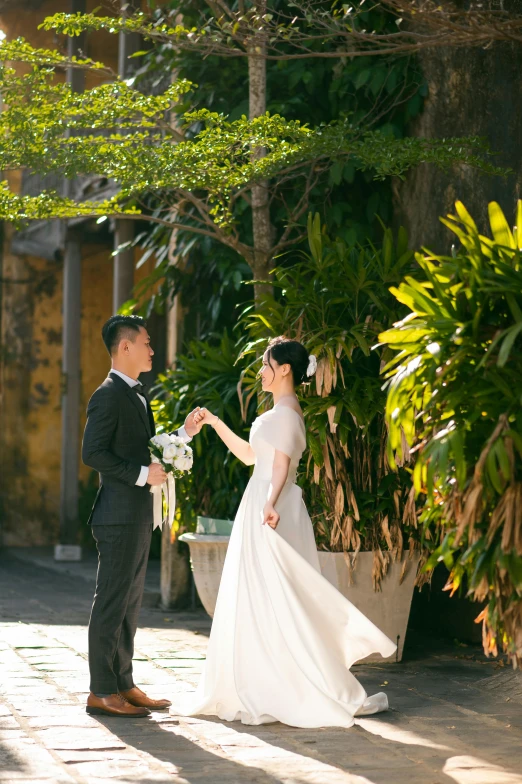 a bride and groom in black suits holding flowers