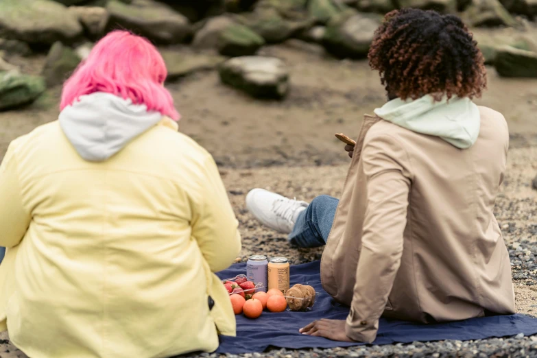 a couple of people sitting on top of a blanket