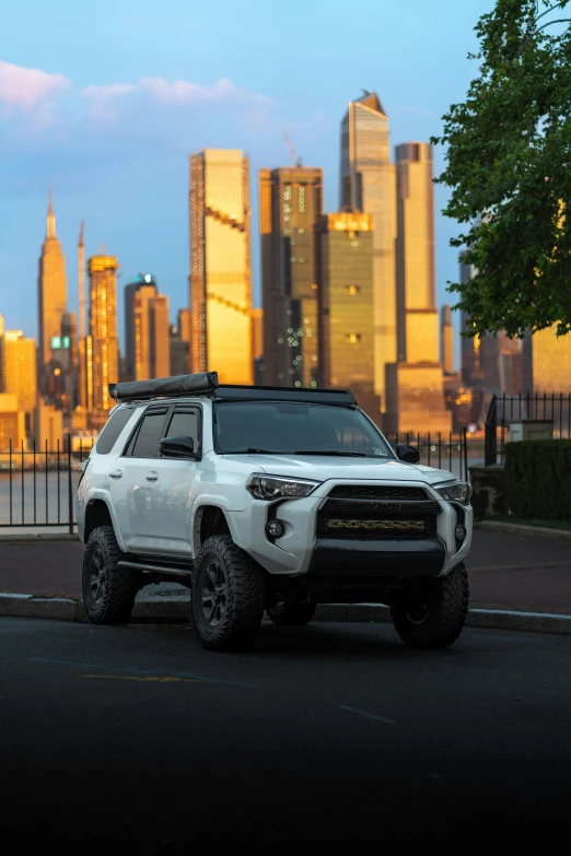 a large white suv on the street near some buildings