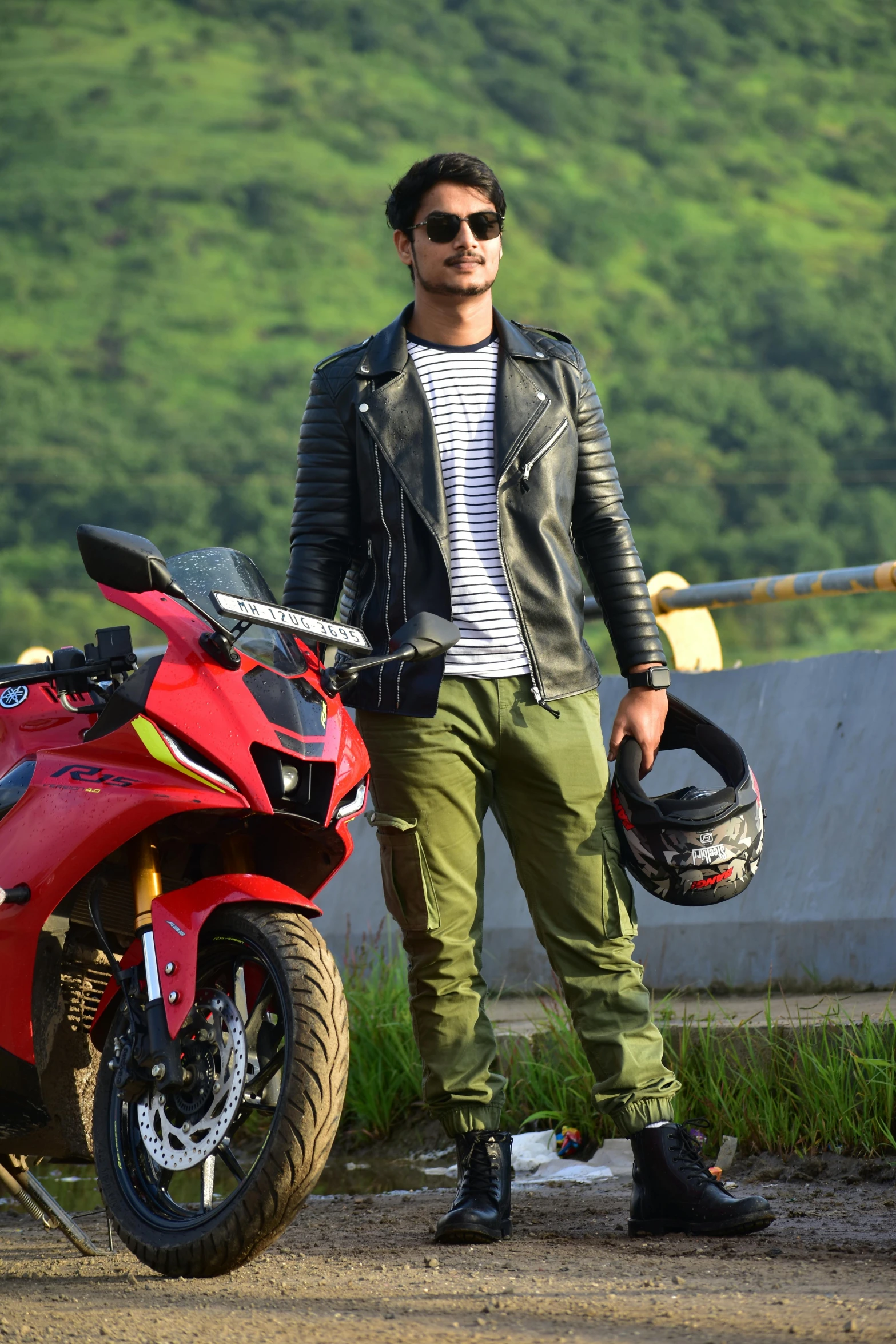 a person in green pants stands next to a red motorcycle