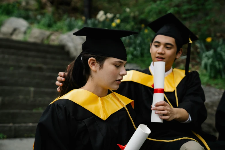 two graduating students read their diplomas in order to get their diploma