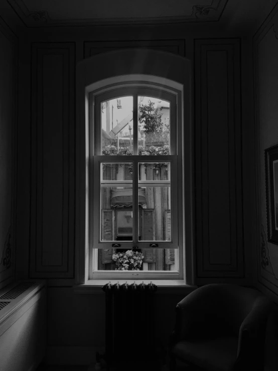 a chair sits by the window of a dark room