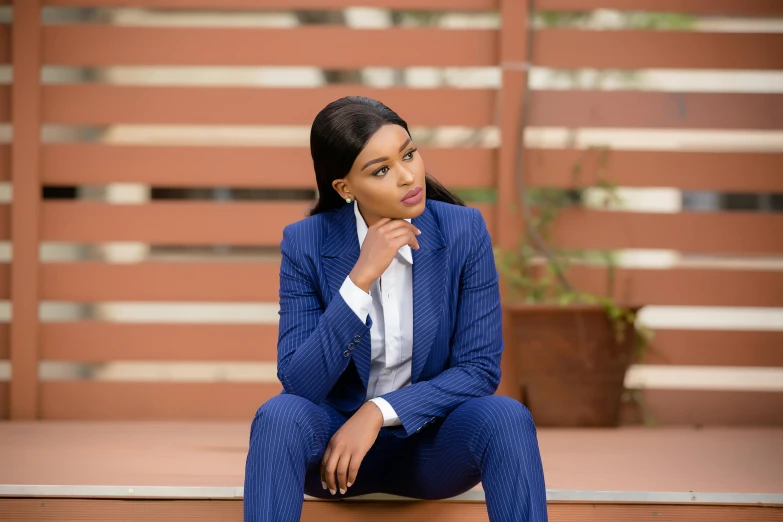 a woman sitting on the ground in a suit