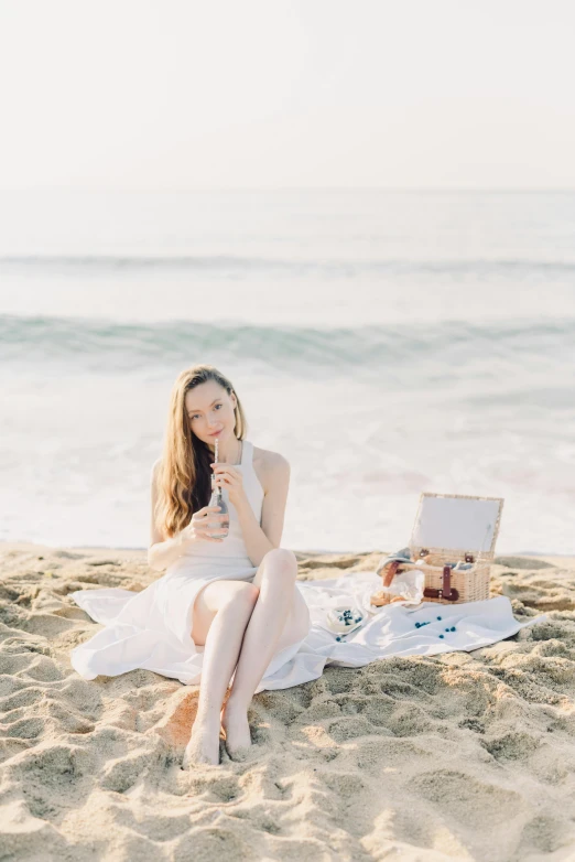 a pretty woman sitting on a towel near the ocean