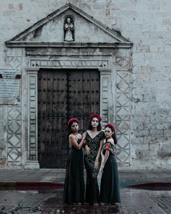 three women in mexican costumes standing together outside a door