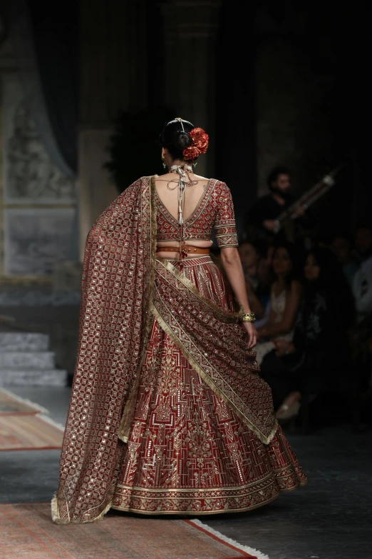 an indian bride in a maroon and gold bridal gown