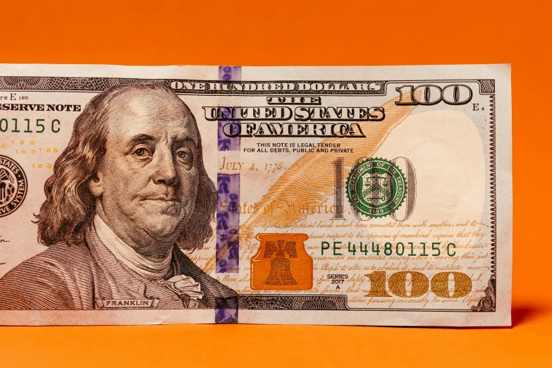 one hundred dollar bill on a red background