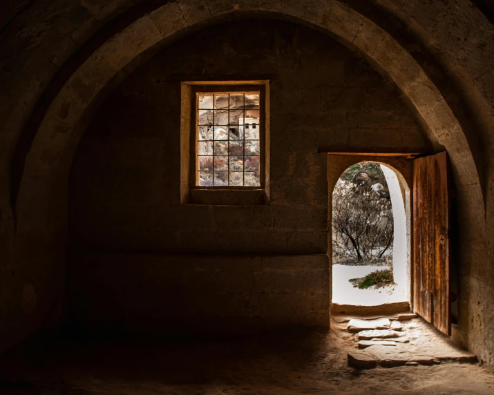 an arched window with a stone floor and dark walls