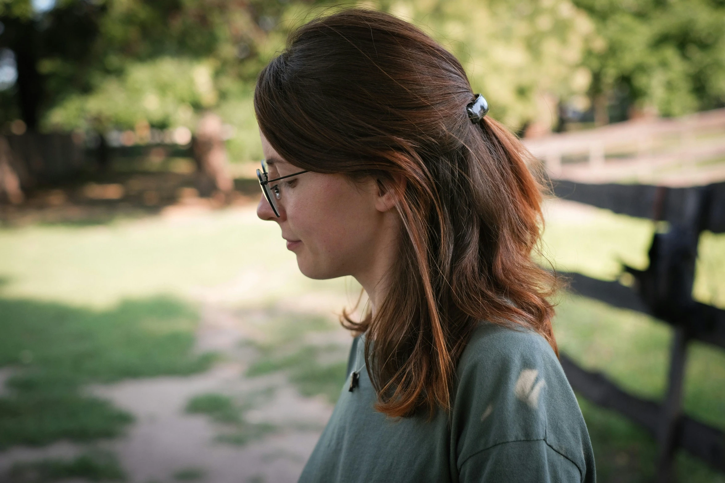 a young woman wearing glasses near a wooden fence