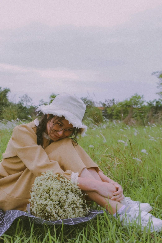 a young woman sitting in a field with flowers