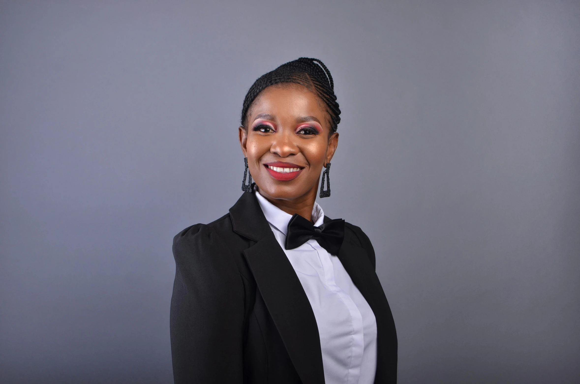 smiling woman in tuxedo standing against a grey background