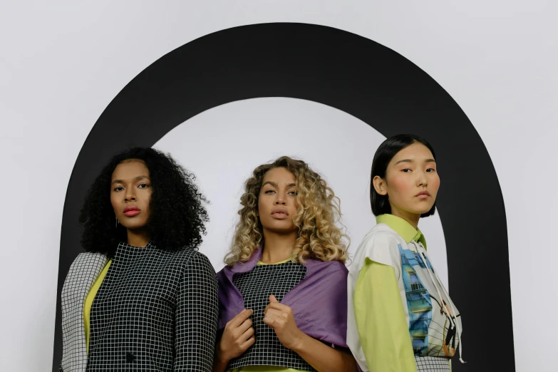 four people standing side by side with different colored dresses on