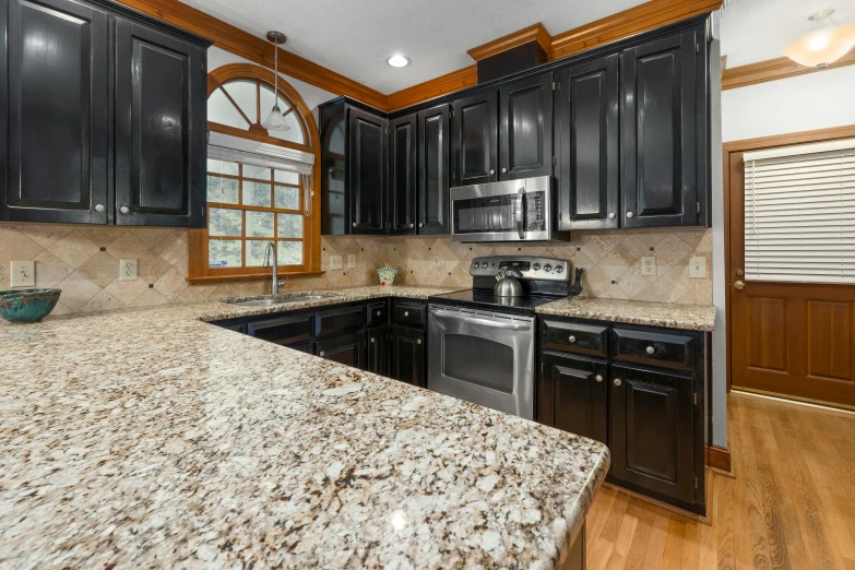 a kitchen with black cabinets and a granite counter