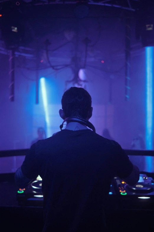 dj performing in a dark room with blue lights
