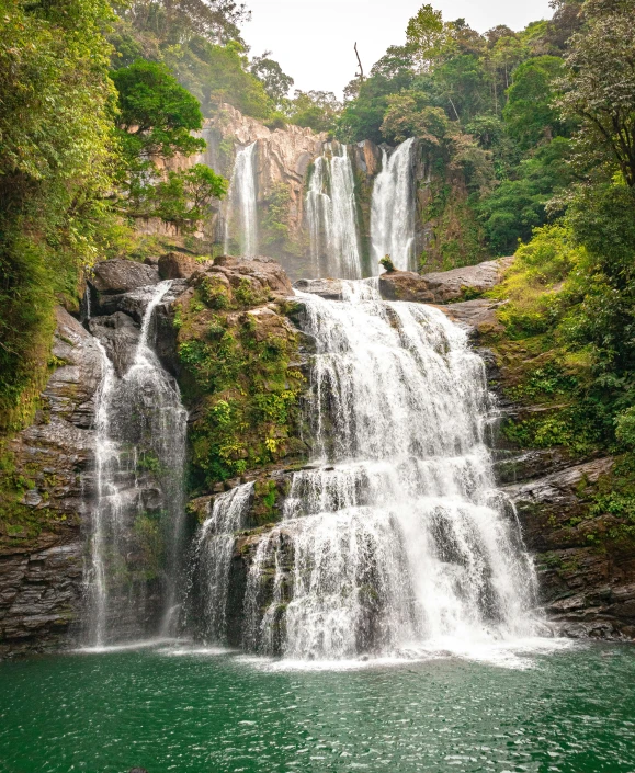 a large waterfall next to a lake surrounded by trees