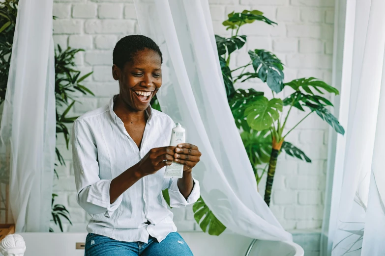 a woman sits on a table next to a plant and holds a cup