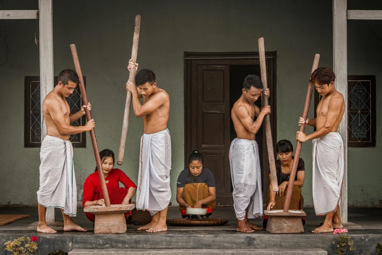 several people holding large wooden sticks near each other