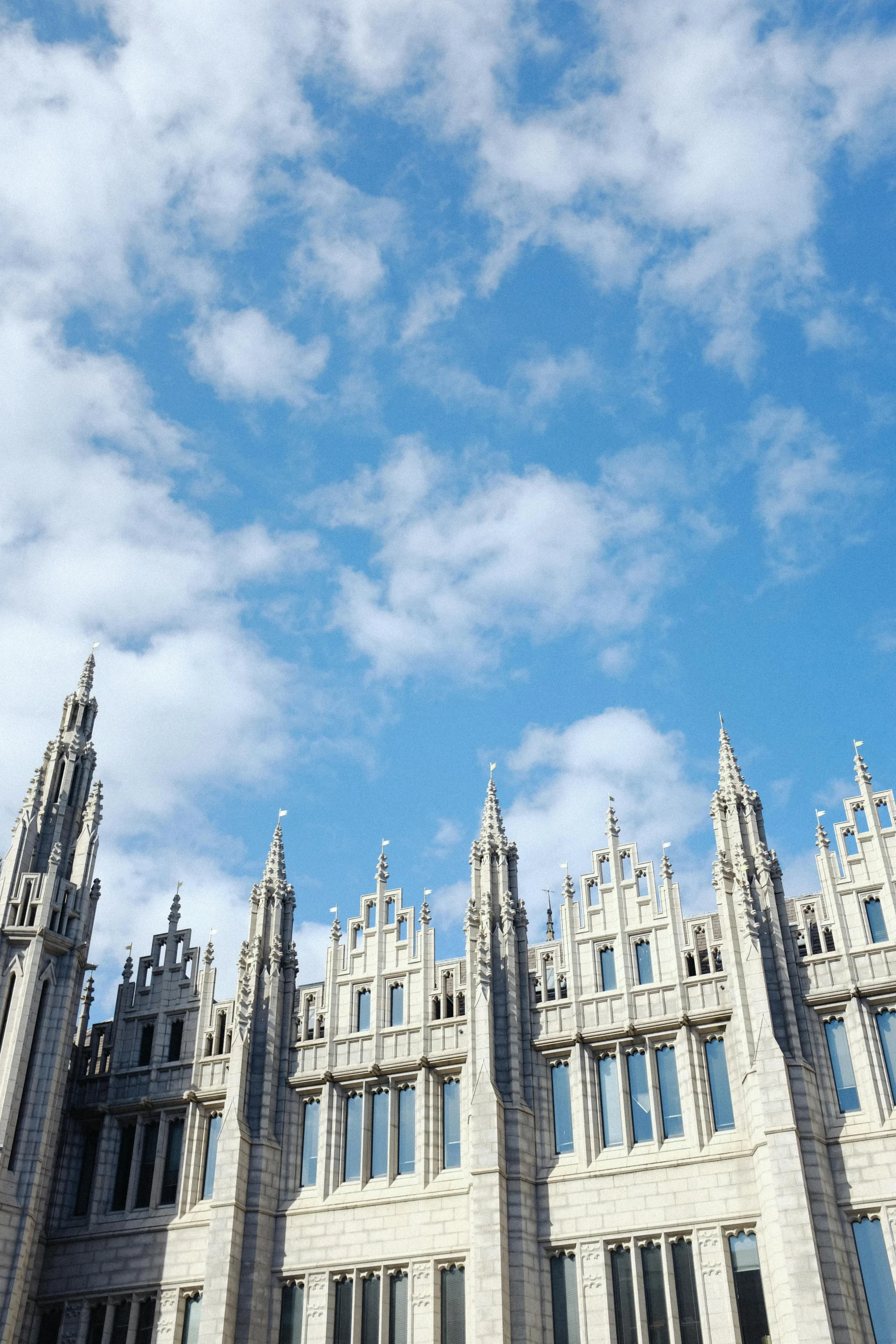 a very tall white building sitting under a cloudy blue sky