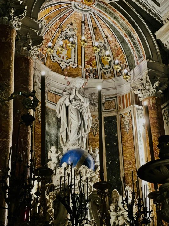 statues stand under a domed ceiling at night