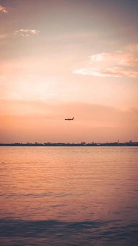 a plane flying high above the water with clouds