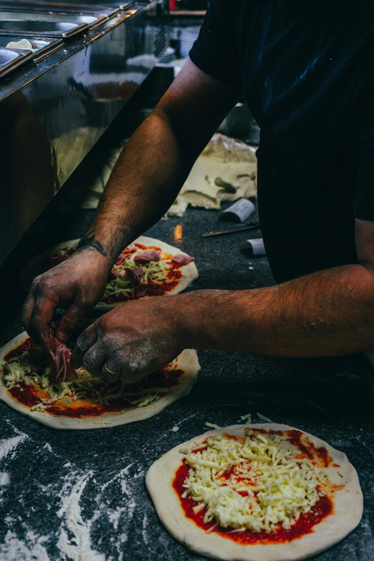 a man making pizzas in a kitchen with a window