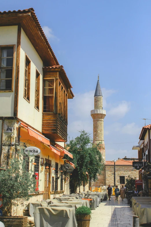 the street has tables and benches along it in front of a large tower