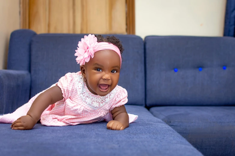 a little baby is on the sofa in pink dress