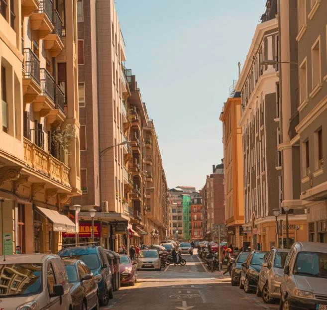 a narrow street with parked cars and buildings in the background