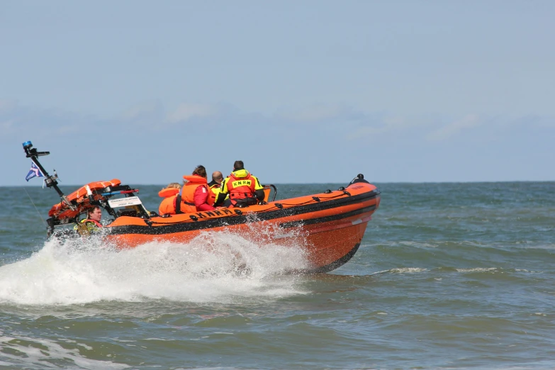 an orange raft carrying people and life vests going across the water