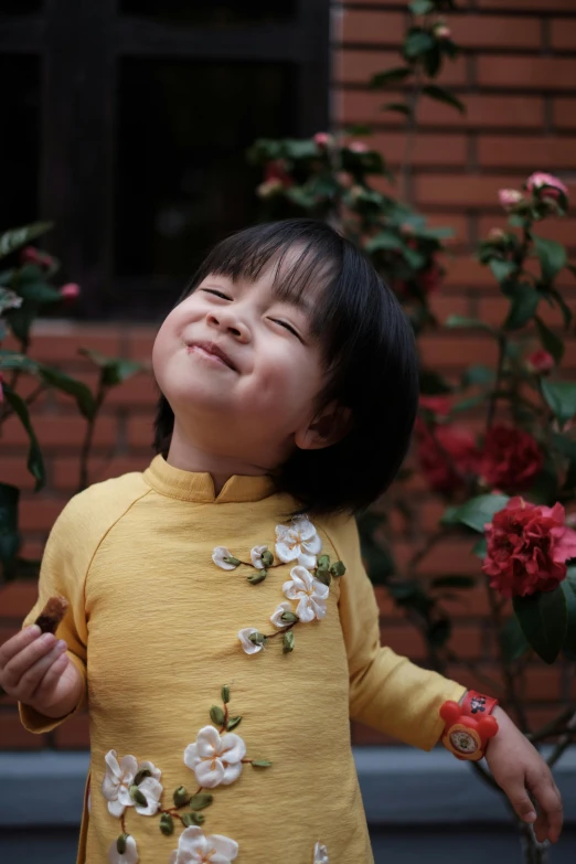 a small child in yellow shirt holding a flower