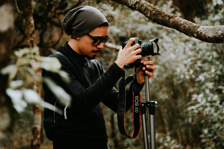 a man in the forest with his camera on a tripod