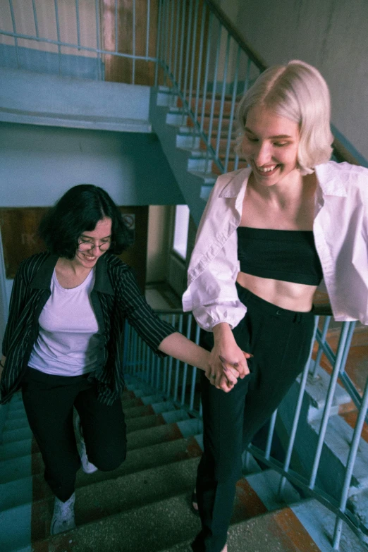 two women are walking up stairs holding hands