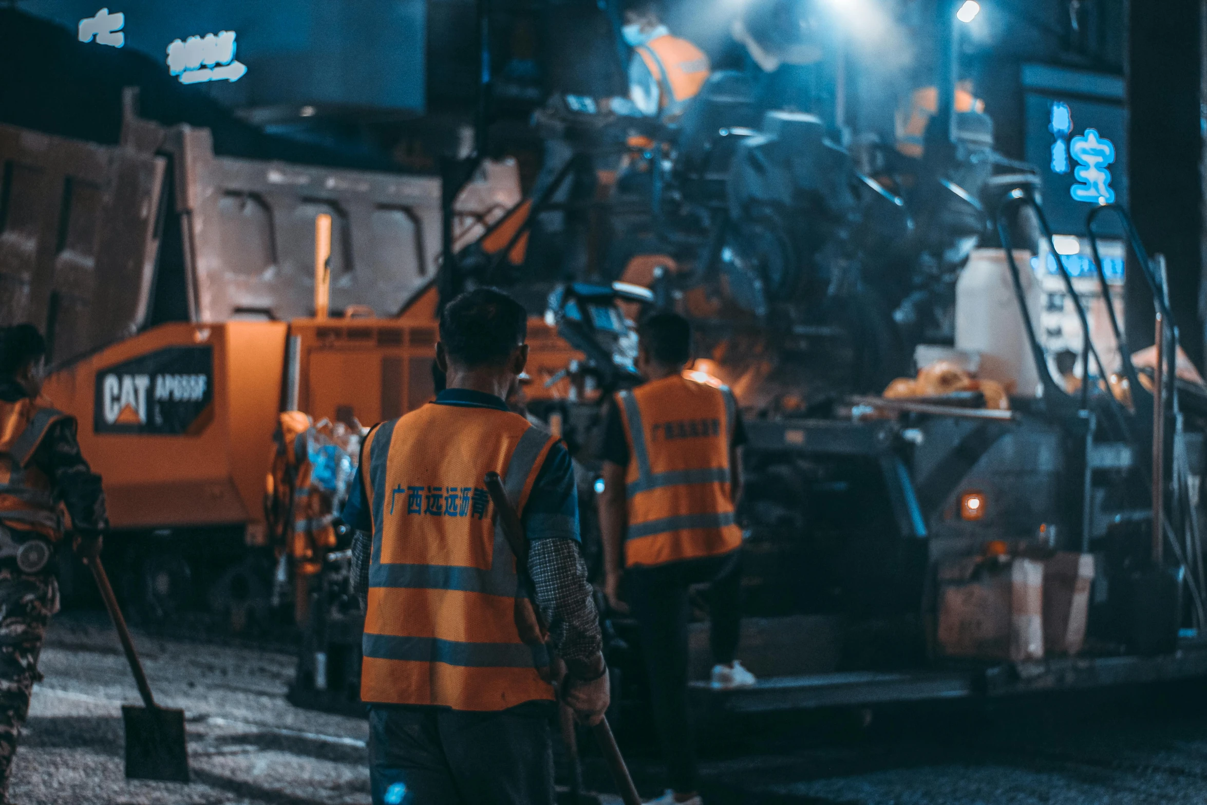 workers in yellow vests are standing next to the back of a work truck