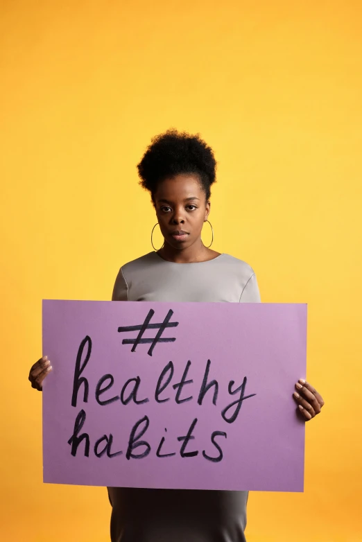 the young woman holding a purple sign that reads healthy habits