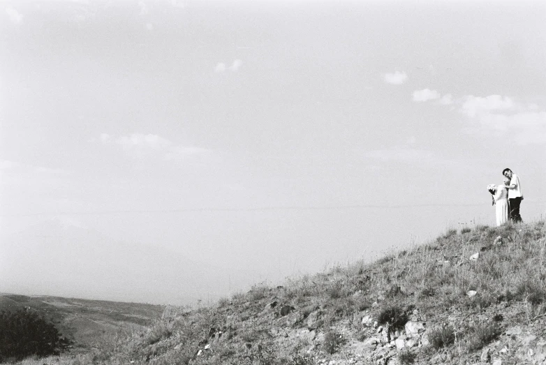 two people stand at the top of a hill