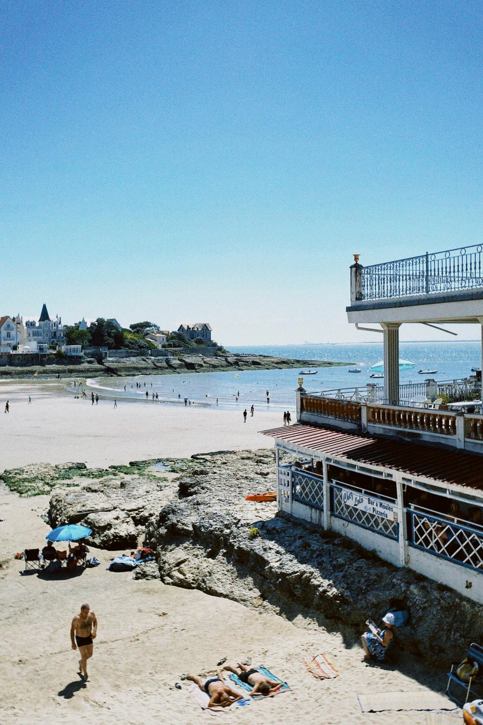 a sandy beach next to the ocean under a blue sky